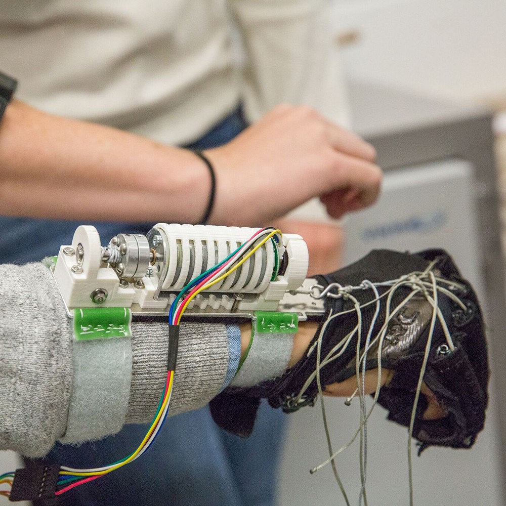 hand being actuated by a black glove with imbedded tethers